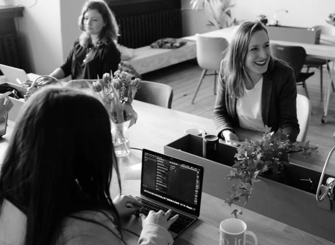 Three women working together at a desk with laptops and data analytics - Mobile view